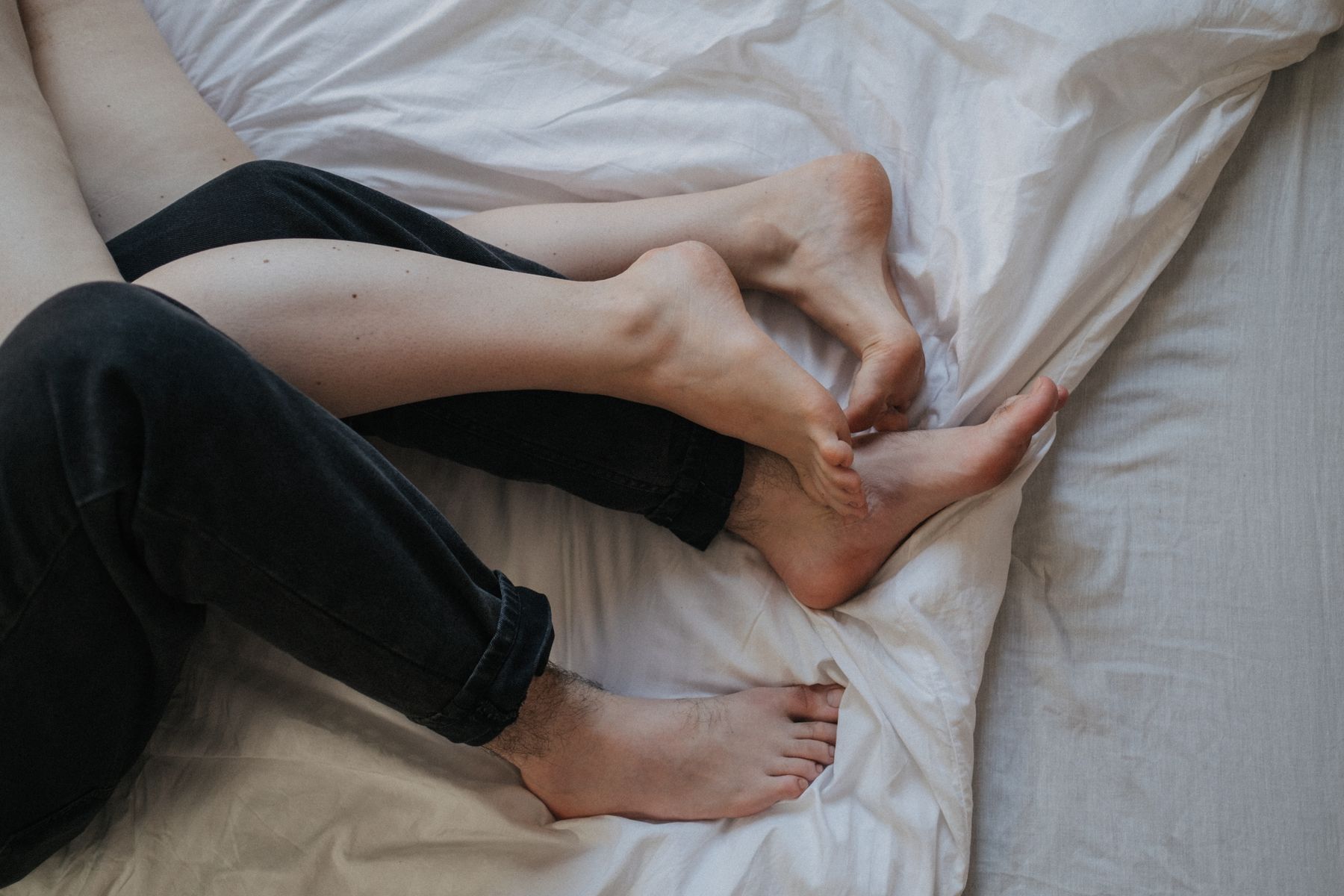 Couple legs intertwined on bed