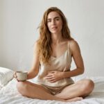 زن در لباس ابریشمی با چای گیاهی در صبح