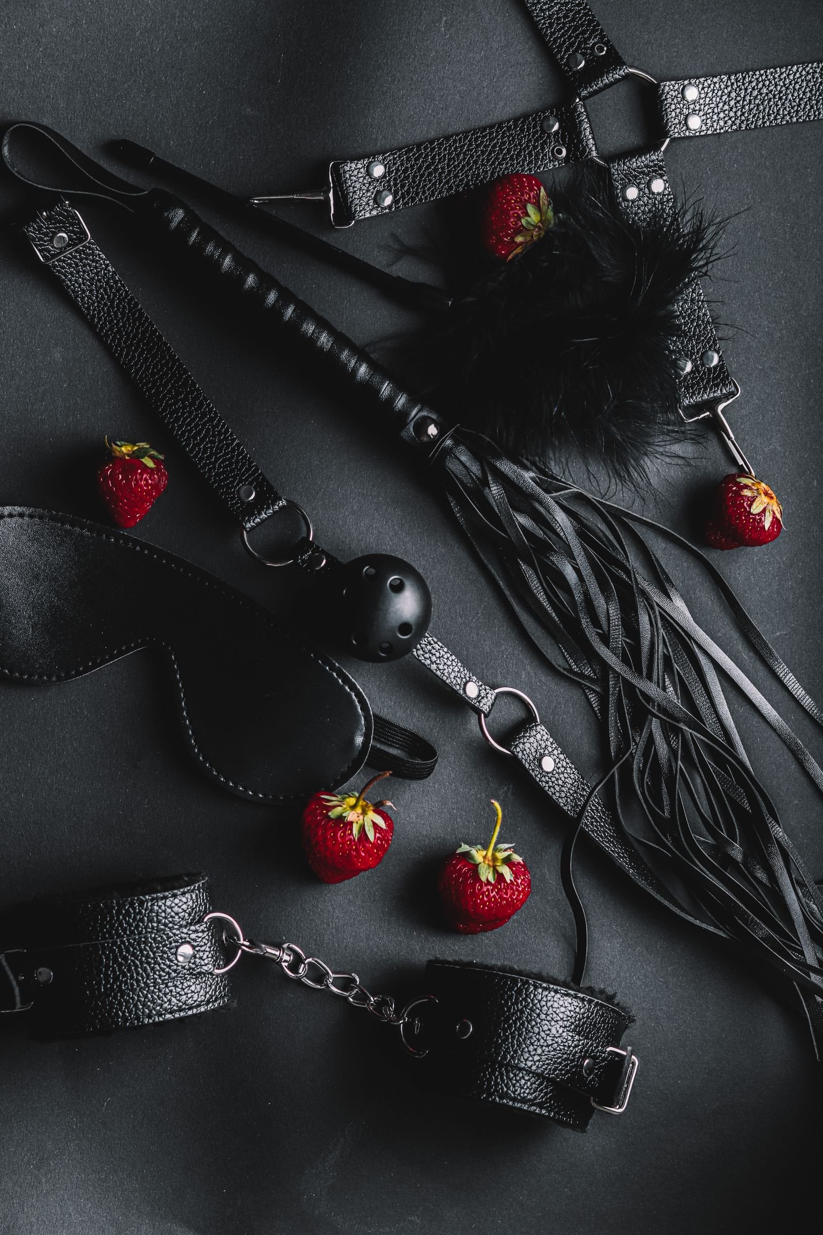 consensual kink safety — leather restraints and accessories arranged on a black background