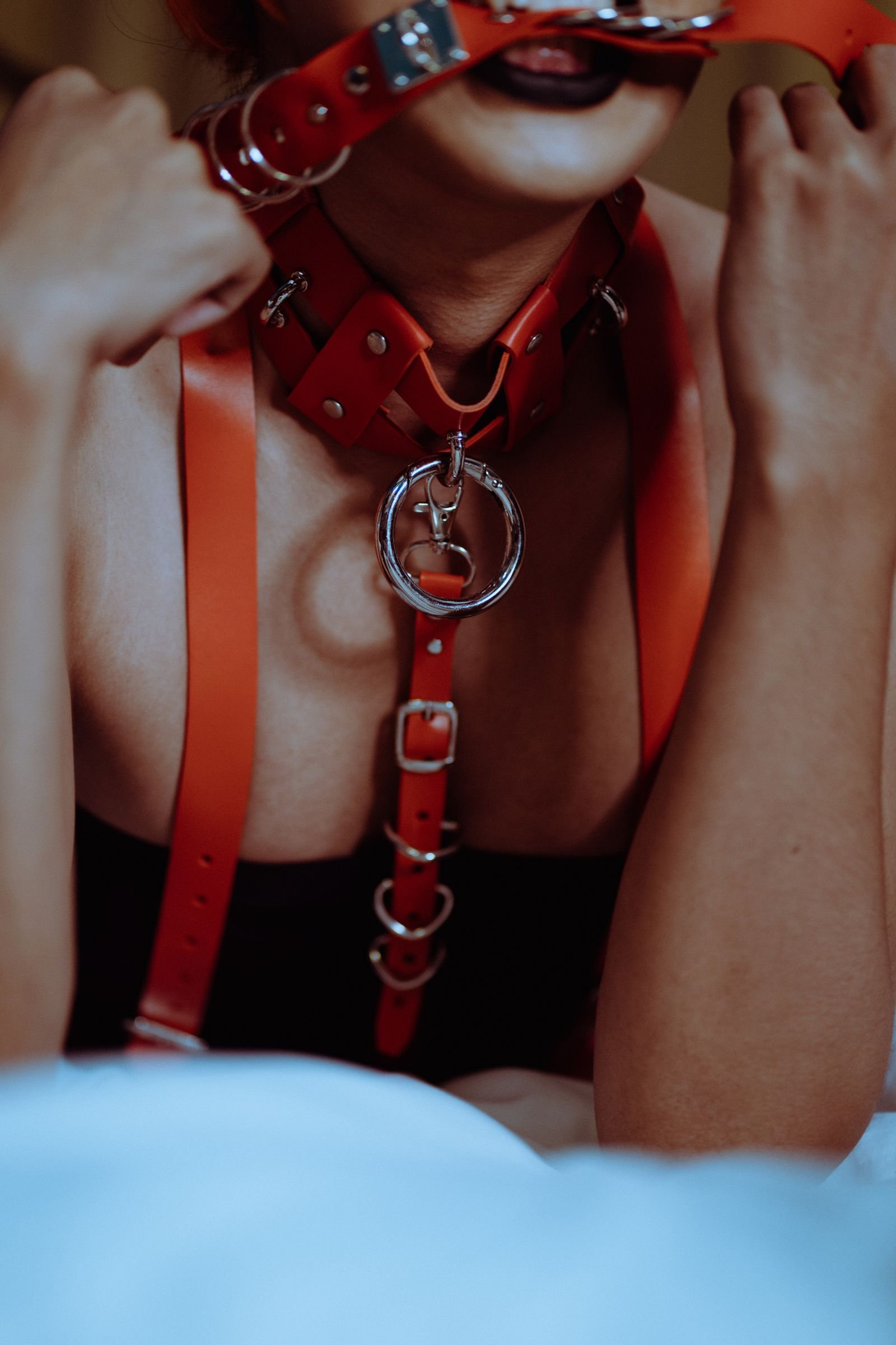 kink aware therapy — close view of a red leather collar and harness worn by an adult, face not shown