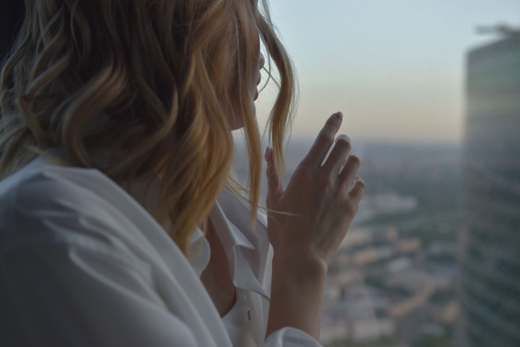 Woman with wavy golden hair in morning light by a window; menopause transition and the body in midlife
