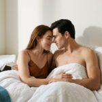 Postpartum Sex: Why Does Desire Return Slowly? زوج جوان در آغوش هم زیر ملحفه در نور صبح؛ بازگشت تدریجی صمیمیت پس از زایمان