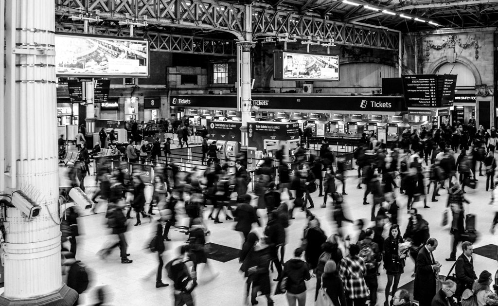 Crowd rushing through a train station, illustrating herd behavior in markets and executive decisions